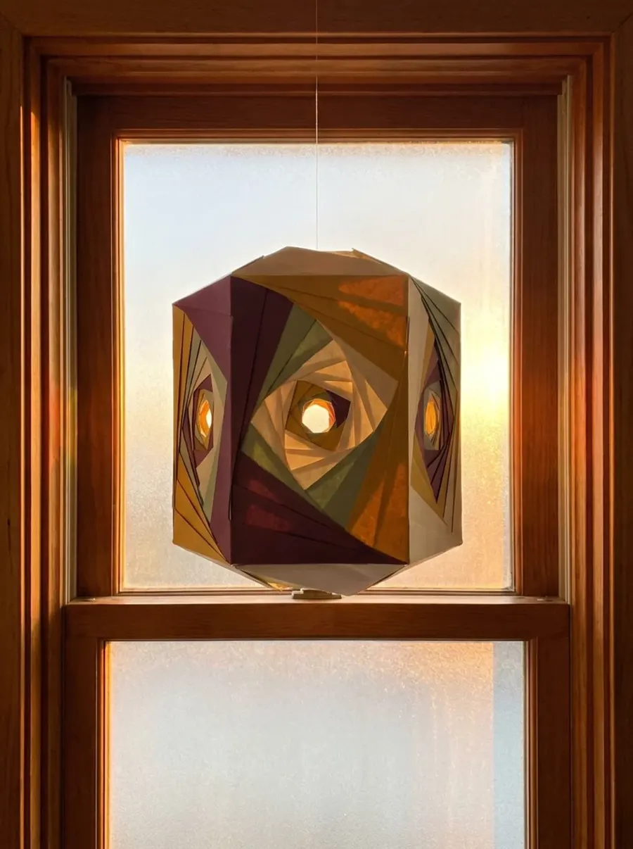 Farol de papel plegado a contraluz en la ventana